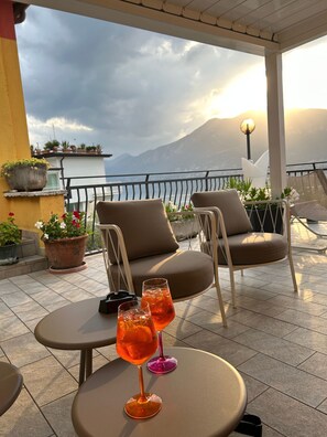 A terrace with two chairs, a table, and two glasses of orange drink.