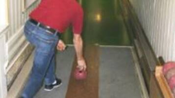 Ein Mann in rotem Hemd und Jeans wischt einen Flur mit einem Mopp aus.