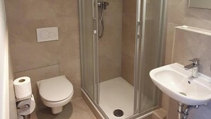 Et moderne badeværelse med bruseniche, toilet og håndvask.