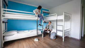Habitación con literas, pared azul, suelo de madera y unidad de aire acondicionado blanca.