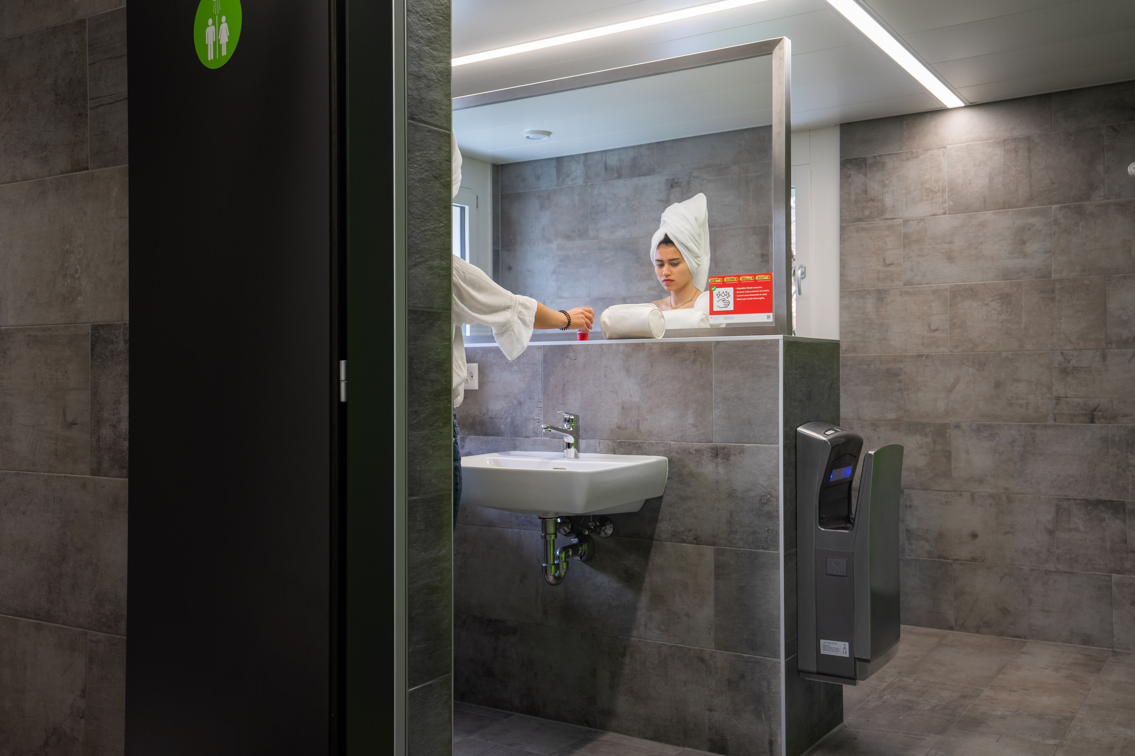 Une salle de bain moderne équipée d’un lavabo, d’un miroir et d’un distributeur de serviettes.