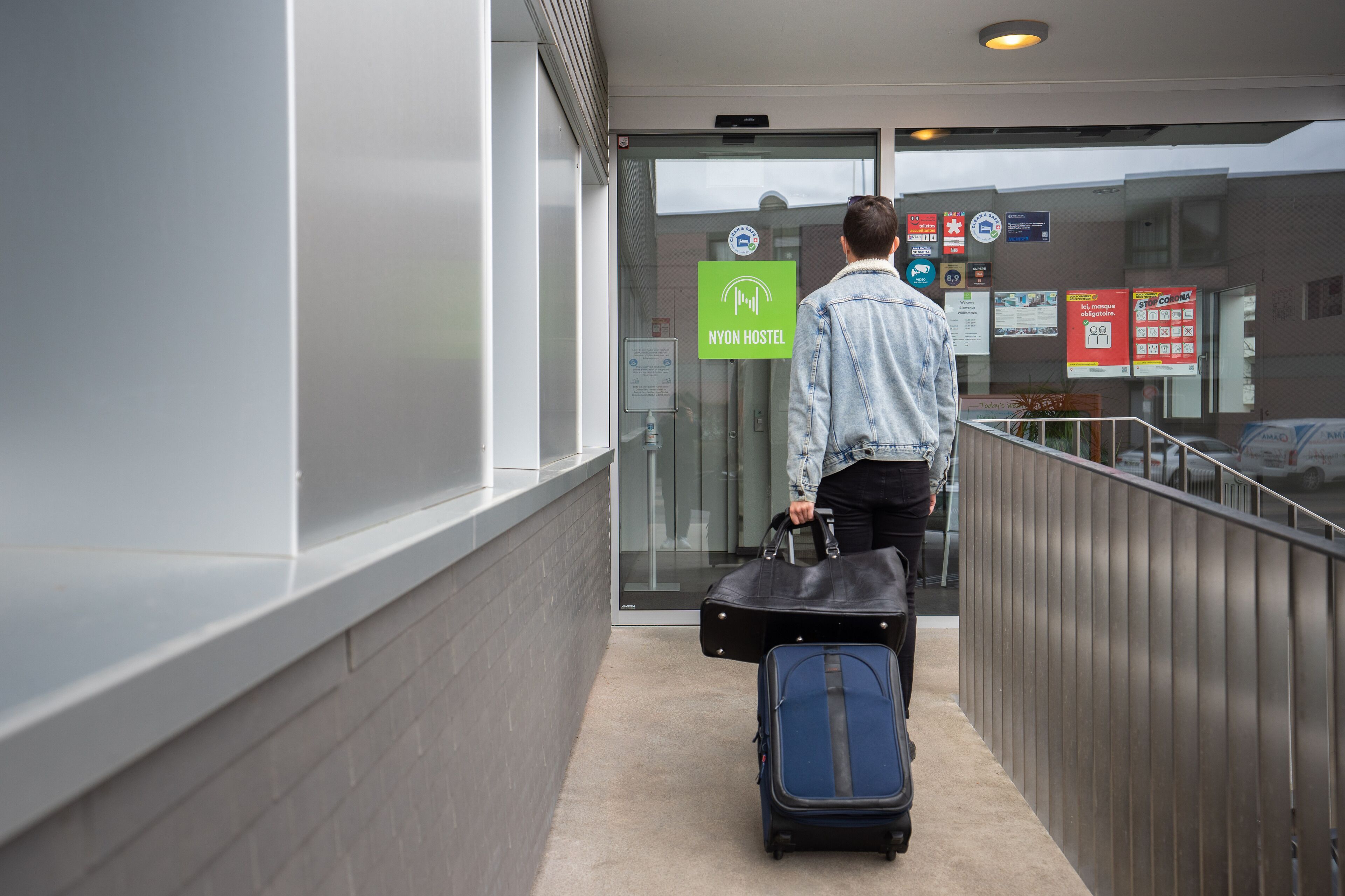 A person with a suitcase at a hostel entrance.
