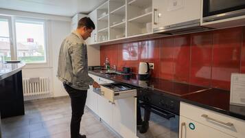 Una cocina moderna con armarios blancos, salpicadero rojo y electrodomésticos de acero inoxidable.