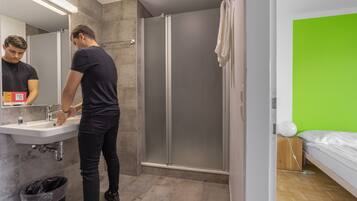 Un baño moderno con lavabo, espejo e inodoro con ducha.