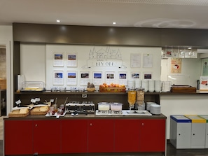 A buffet area with various food items, a welcome sign, and informational posters. - Nyon Hostel (Nyon)