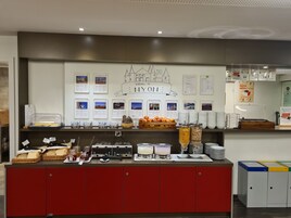Zona de buffet con diferentes opciones de comida, un cartel de bienvenida y carteles informativos.