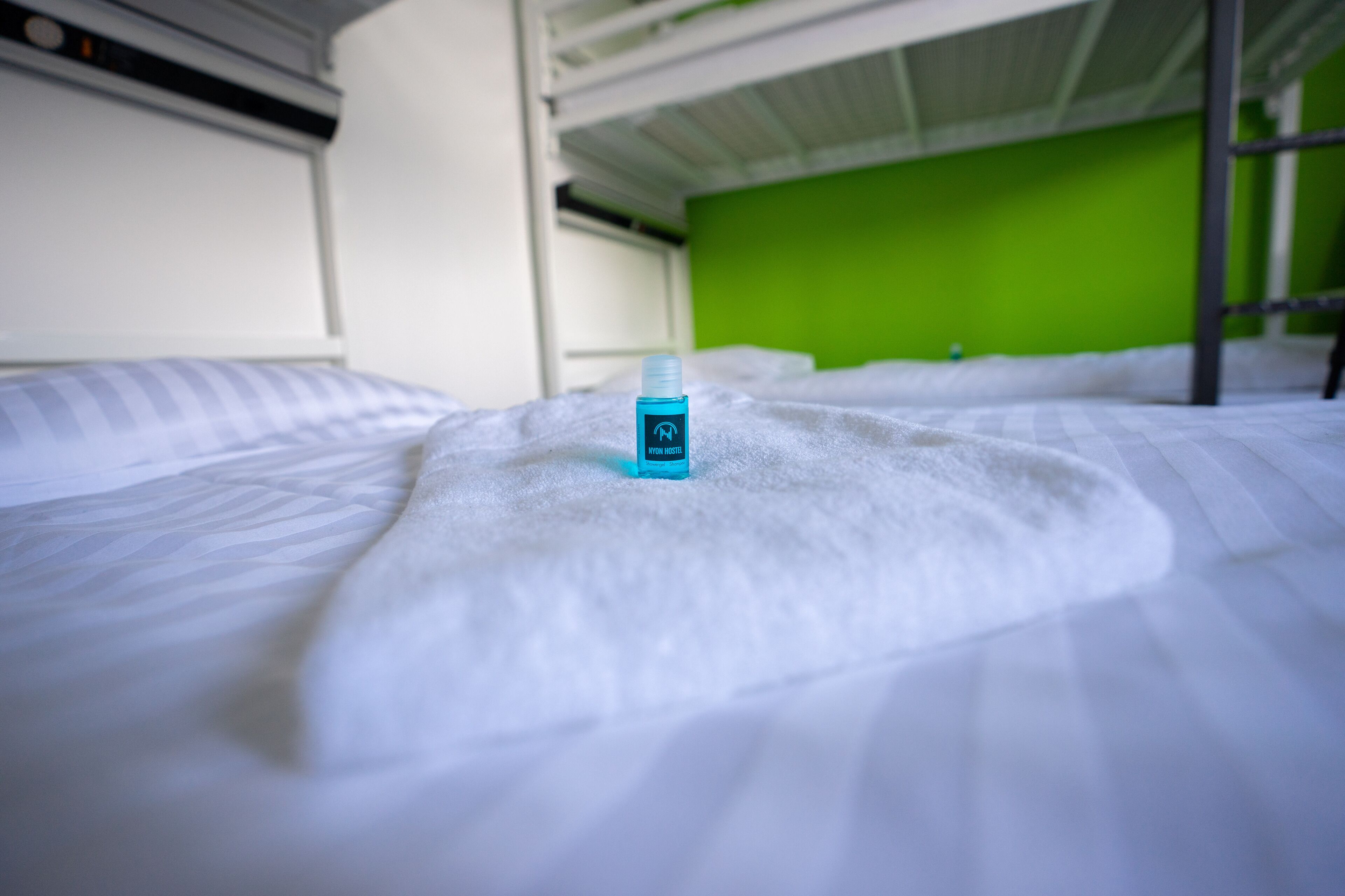 Una cama con una colcha blanca y una botella azul encima.