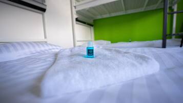 Una cama con una colcha blanca y una botella azul encima.