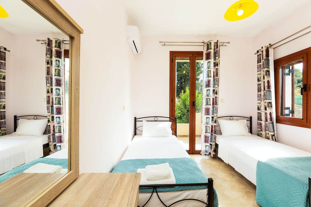 A room with two single beds, a wooden table, and a mirror.