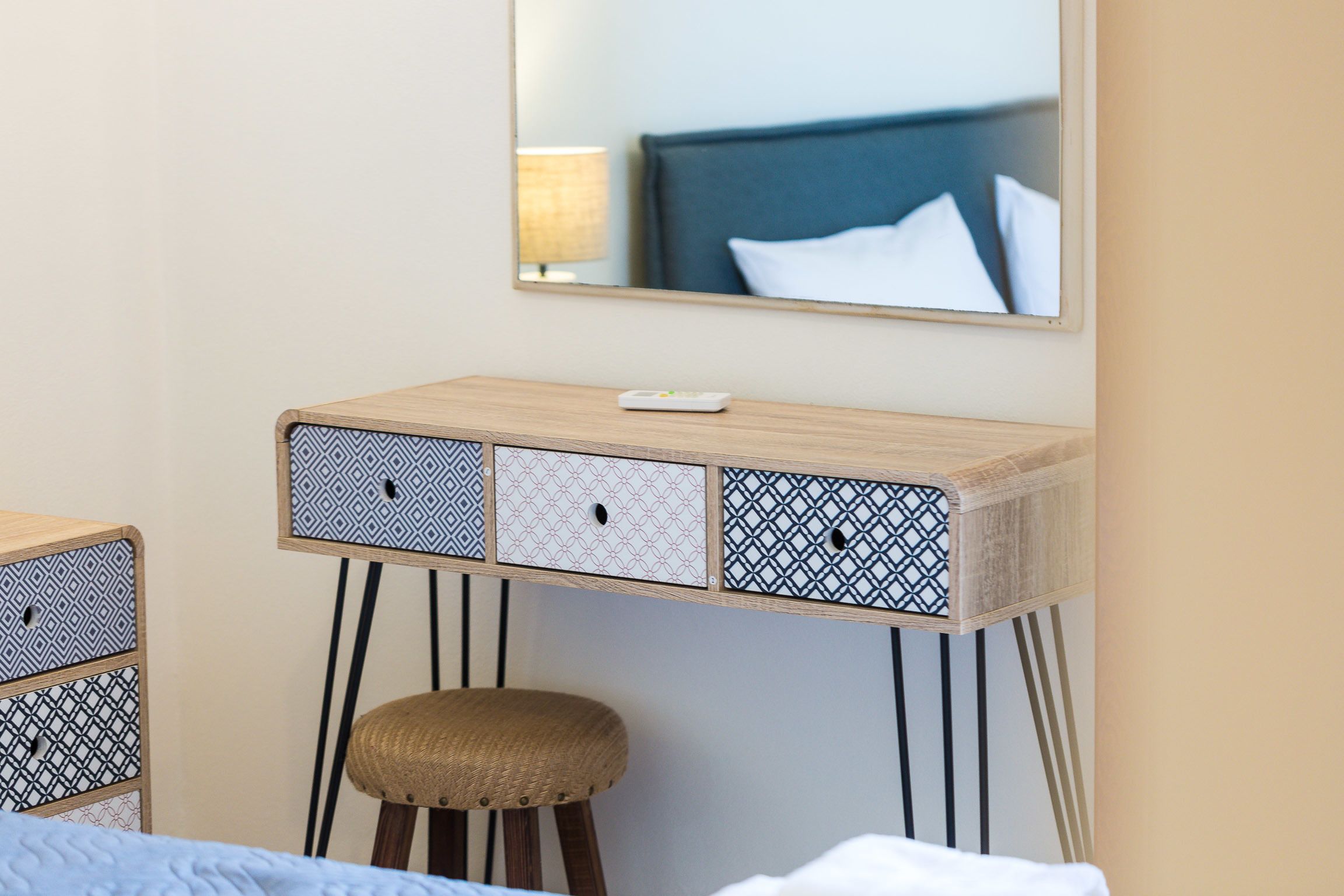 A compact hotel room with a wooden desk, a stool, and a bed.
