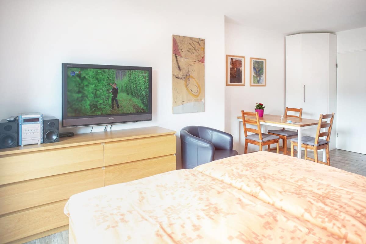Ein Hotelzimmer mit Bett, Fernseher, Schreibtisch und Stuhl.