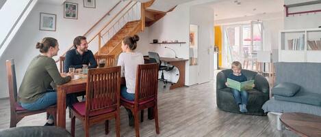 Un salon moderne comprenant un coin repas, un escalier et un coin lecture.