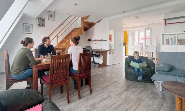 Una sala de estar moderna con comedor, escalera y un rincón de lectura.