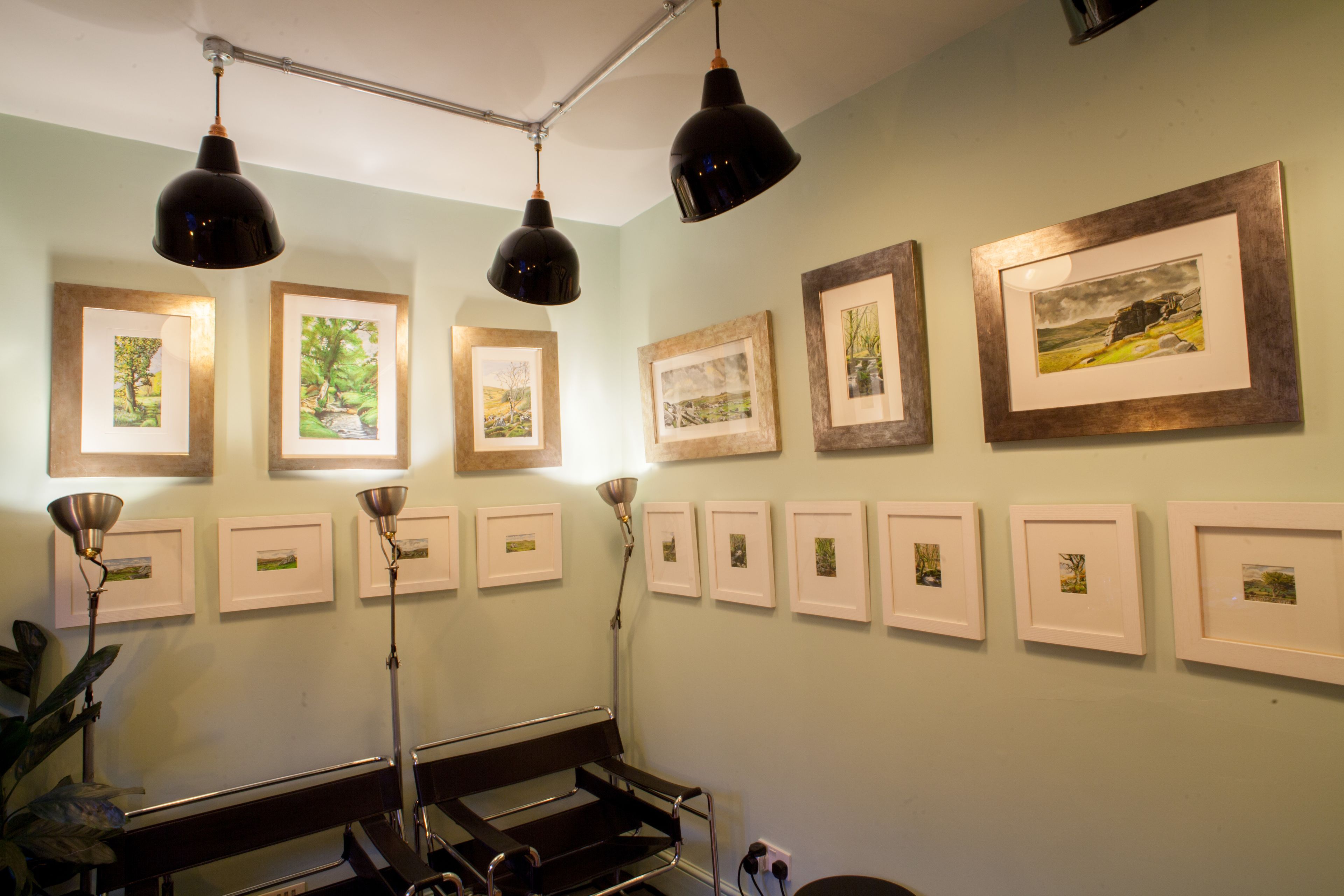 Una galería con obras de arte enmarcadas en las paredes y un banco al frente.
