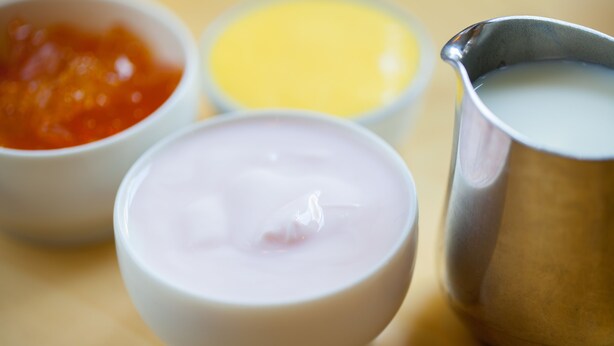 A close-up of three bowls containing different colored substances, likely food items, on a wooden surface.