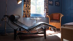 A room with a modern chaise lounge, a small round table, and a wicker chair. - Hill View House (Dartmouth)