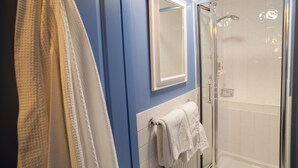 A bathroom with a glass shower enclosure, a white towel rack, and a blue wall.