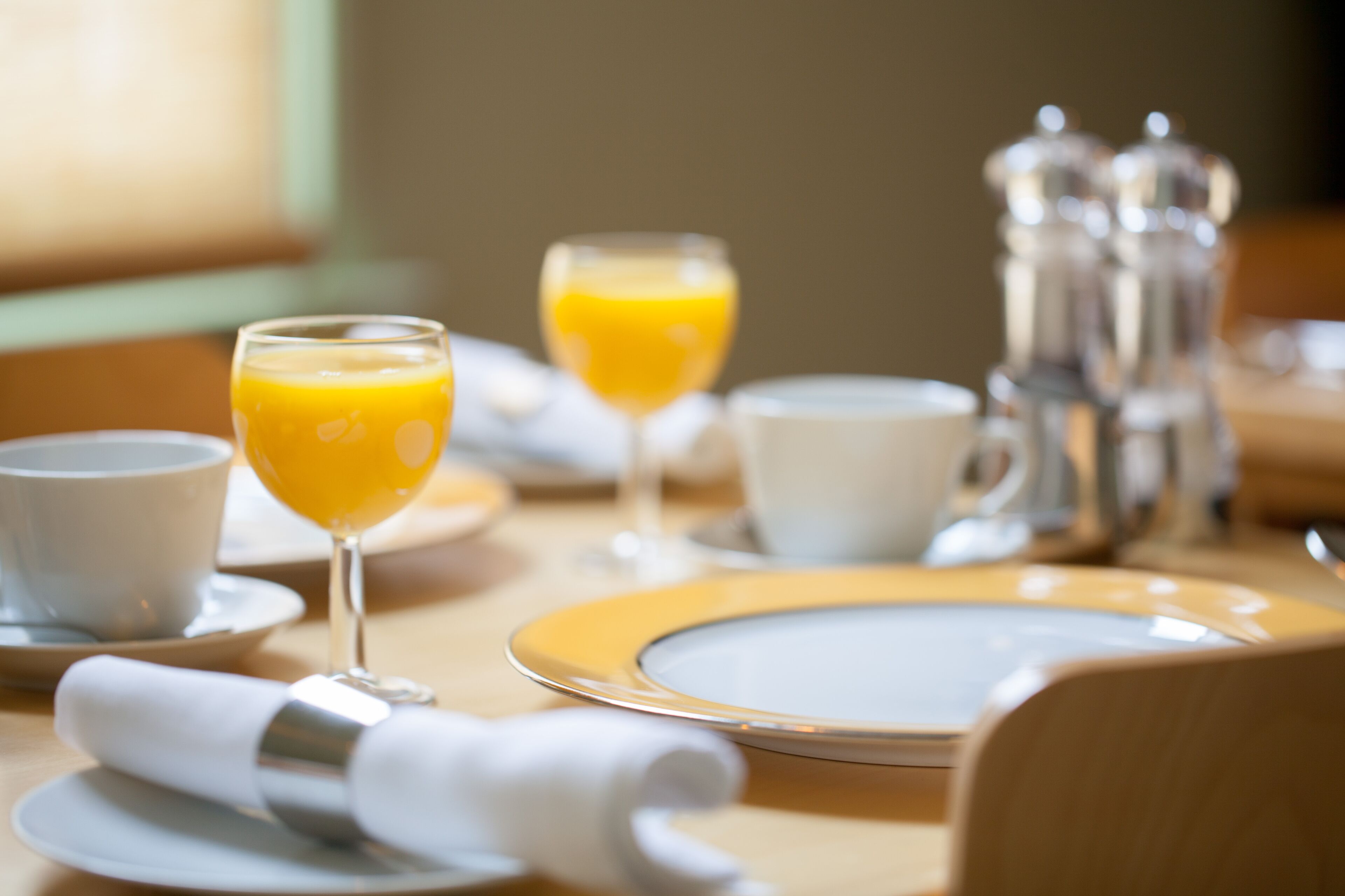 A breakfast setting with plates, glasses, and a coffee pot.
