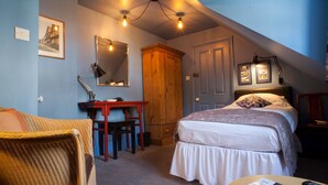 A bedroom with a bed, a desk, a chair, a wardrobe, and a mirror.