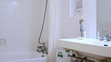 A bathroom with a toilet, a shower, and a sink.