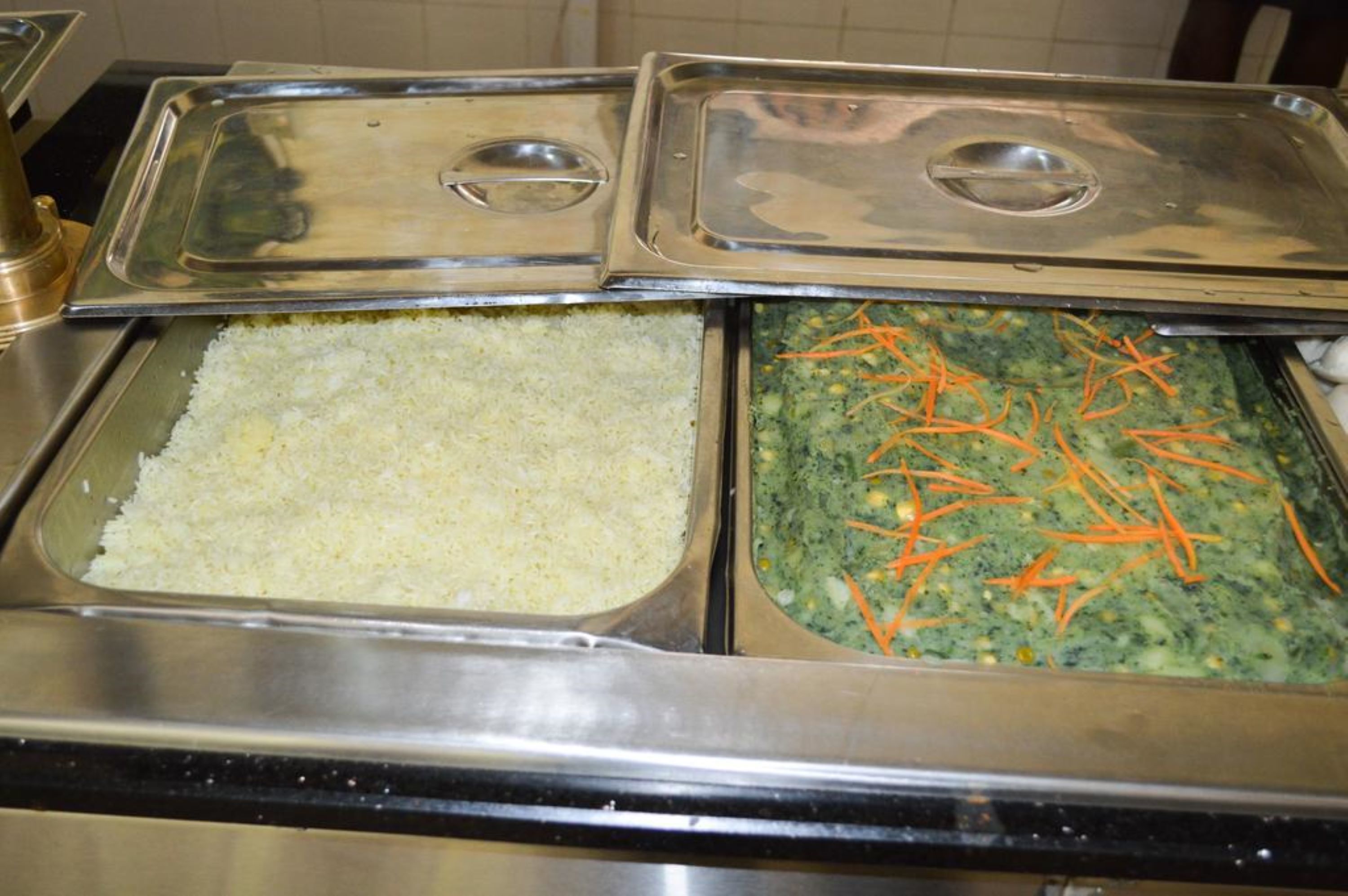 A buffet with two covered dishes, one with rice and the other with a green vegetable mixture.