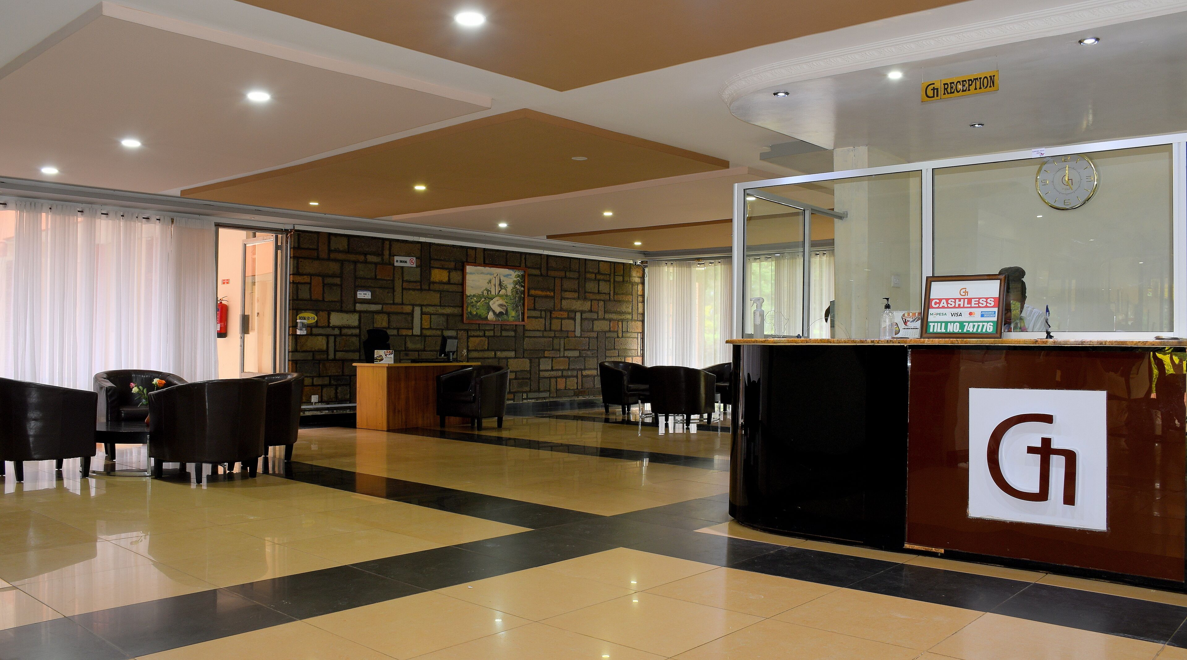 A reception area with a reception desk, black chairs, a stone wall, and a clock.