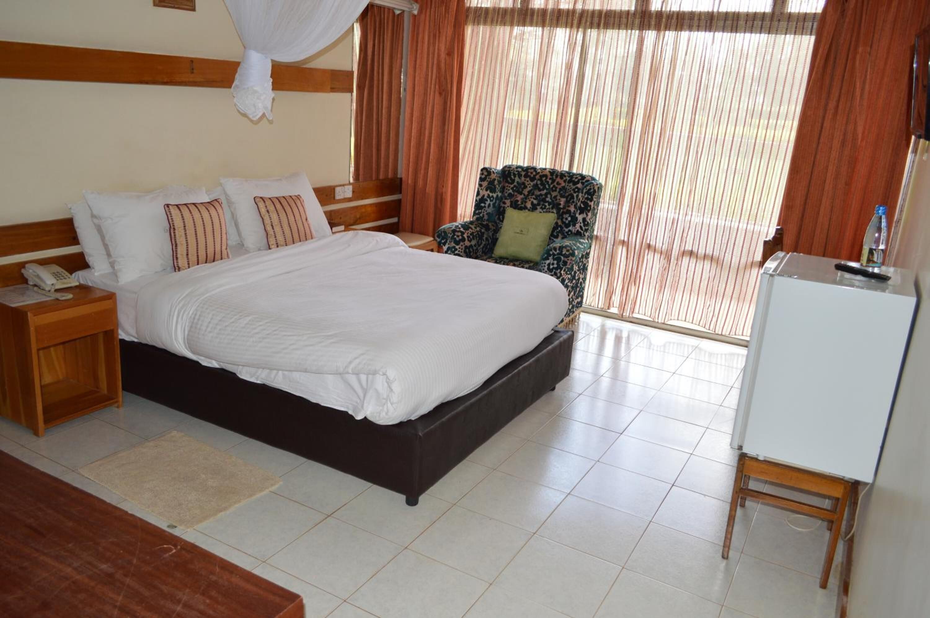 A bedroom with a large bed, a chair, a bedside table, and a whiteboard.