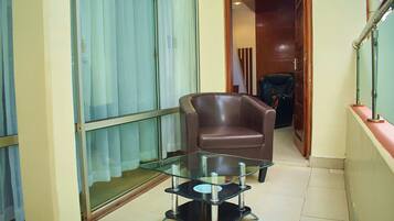 A small living area with a glass coffee table, a leather armchair, and a sliding glass door.