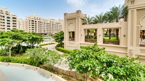 A modern hotel with a courtyard featuring lush greenery and a pool. - Fairmont North Luxury 2 BR Apt Palm (Dubai)