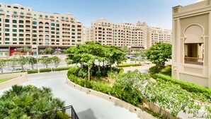 A residential area with modern buildings, a curved road, and lush greenery. - Fairmont North Luxury 2 BR Apt Palm (Dubai)