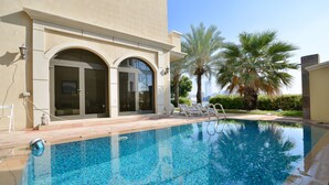 Una piscina al aire libre, sillones reclinables de piscina