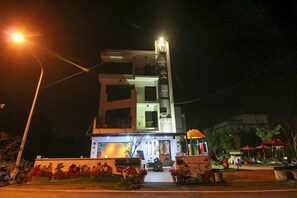 A modern hotel with a prominent vertical sign, a well-lit entrance, and a decorative wall with figures. - Ark Stay (Jiji)