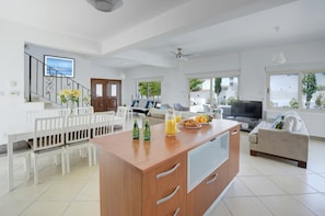A modern living room with a dining area, a kitchen island, and a sofa.