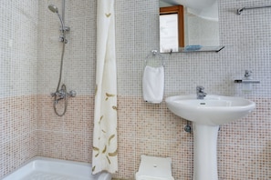 Un baño con bañera, ducha, lavamanos e inodoro.