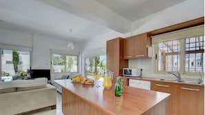 Une cuisine moderne avec des meubles en bois, un îlot central et un coin repas doté d’un canapé.