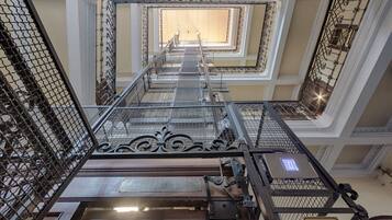 Een meerlaags interieur met metalen hekwerk, een centrale trap en een bord met een symbool.
