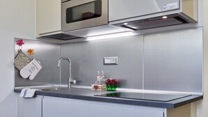 Una cocina moderna con extractor de acero inoxidable, microondas integrado y encimera con lavaplatos.