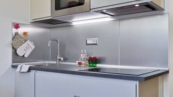 Una cocina moderna con extractor de acero inoxidable, microondas integrado y encimera con lavaplatos.
