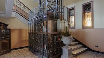 Una escalera con barandillas metálicas ornamentales, una planta en maceta y una urna decorativa.