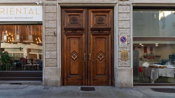 Una puerta doble de madera tradicional con tallas intrincadas, un letrero de restaurante japonés y una señal de no estacionamiento.
