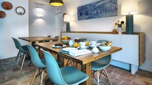 A dining area with a wooden table, teal chairs, and a fruit bowl. - Alte Tradition Guest House (Loulé)