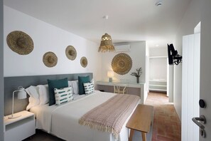 A bedroom with a bed, bedside table, lamp, and decorative wall hangings. - Alte Tradition Guest House (Loulé)