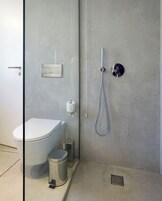 Un baño moderno con inodoro, ducha y mampara de vidrio.