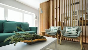 A modern living room with a green sofa, two armchairs, a white coffee table, and a wooden partition. - Alte Tradition Guest House (Loulé)