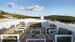A rooftop terrace with white furniture, a small tower, and a view of the countryside. - Alte Tradition Guest House (Loulé)
