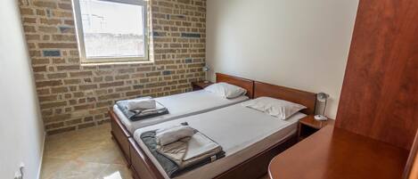 Uma cama de casal com cabeceira de madeira, mesa de cabeceira, abajur e janela com persianas.