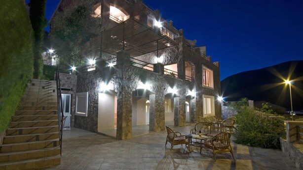 A multi-story building with outdoor seating and a staircase leading to the entrance. - Contessa Apartments (Budva)
