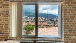 A room with a large window overlooking a cityscape and mountains. - Contessa Apartments (Budva)