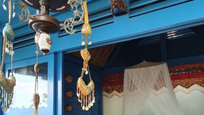 Una habitación con cama, paredes azules, una lámpara colgante y una alfombra colorida.