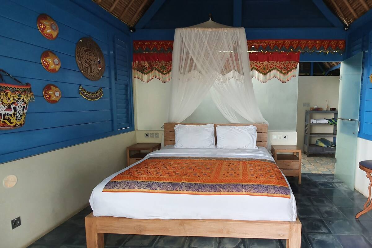 Una habitación con cama, una silla, mesita de noche y armario.